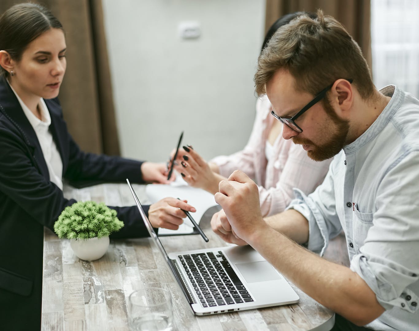 un homme et une femme assis à une table et travaillant sur un ordinateur portable