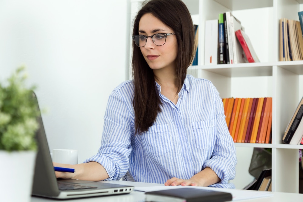 une femme assise à un bureau utilisant un ordinateur portable