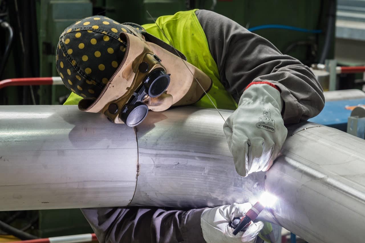 soudeur travaillant sur un tuyau dans une usine